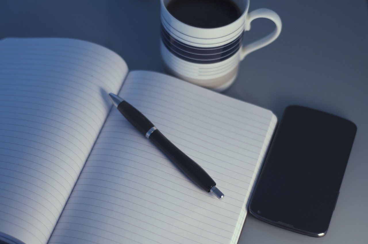 Cuaderno de trabajo, café y teléfono para una sesión de acompañamiento